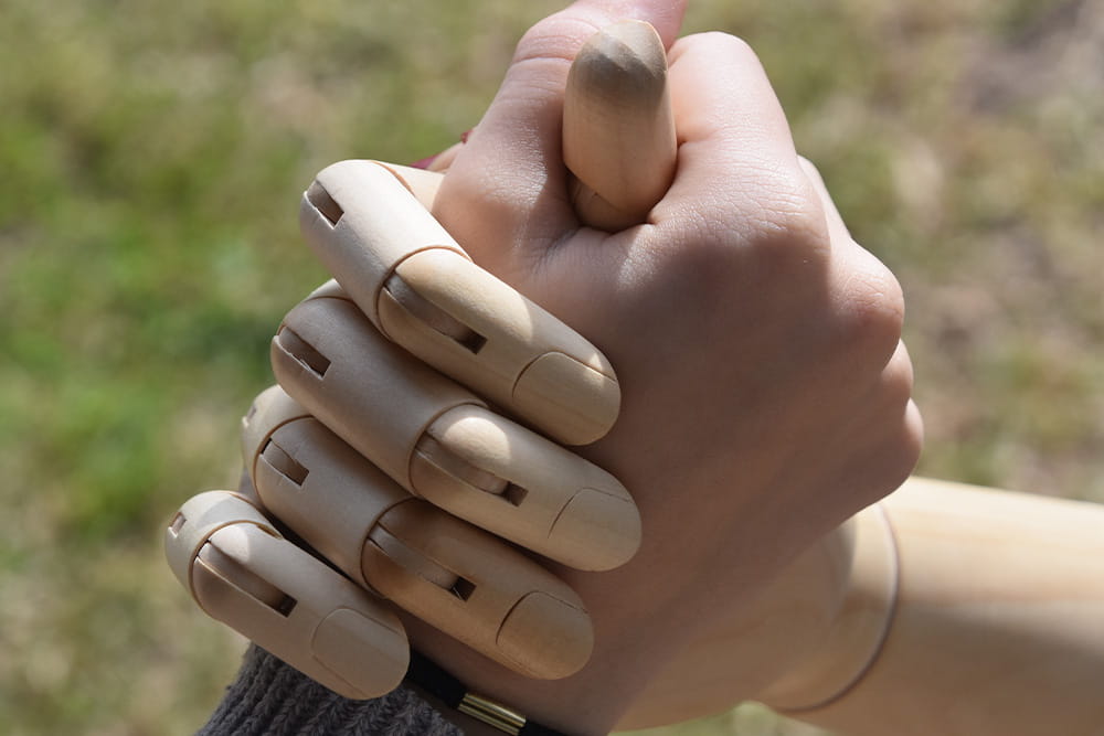 Eine Menschenhand und eine Holzhand greifen Hand in Hand