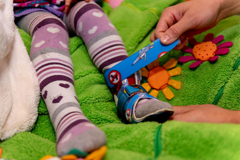 Einem kleinen Kind wird eine Fußorthese angepasst