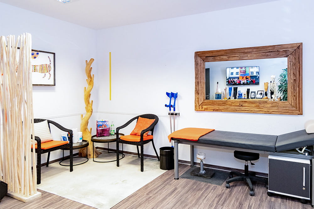 Ein Behandlungsraum mit Korbsesseln und einer Liege.