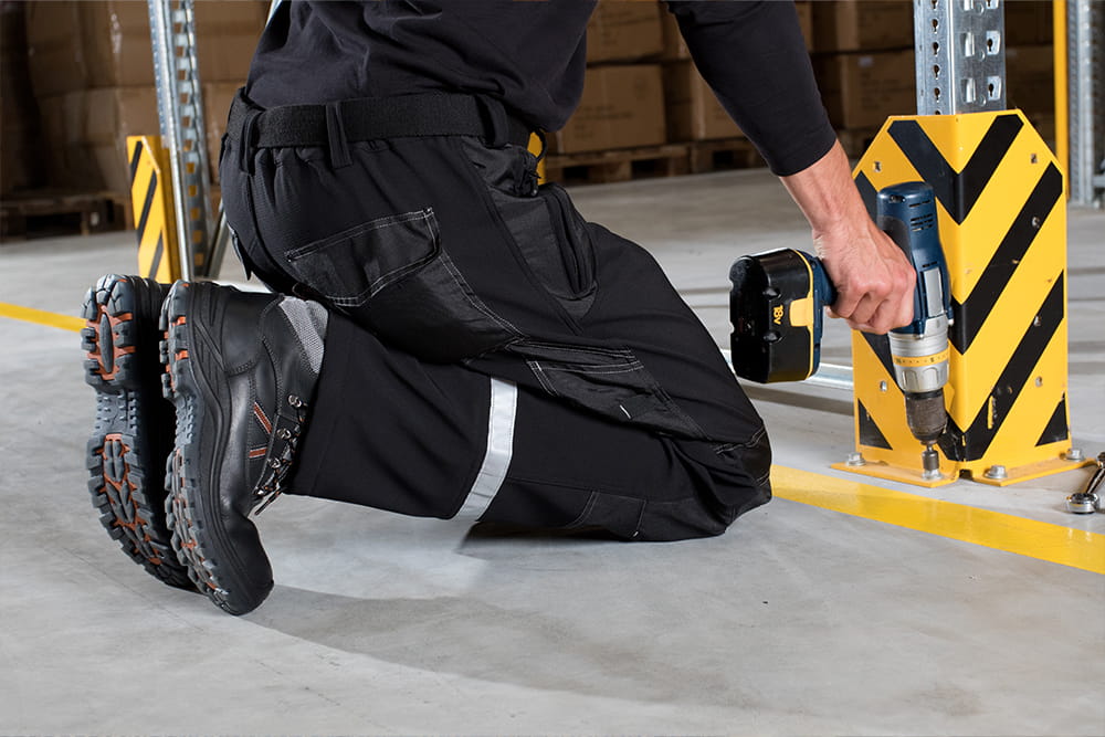 Ein Mann hockt auf dem Boden und schraubt eine Halterung fest.