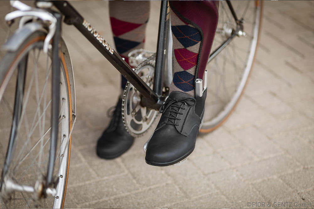 Ein Mann mit auffälligen Socken trägt sichtbar seine Beinorthese und fährt dabei Fahrrad.