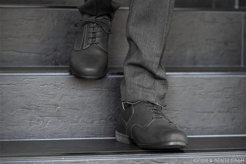 Ein Mann mit dunkler Hose und dunklen Schuhen steigt Treppen herunter.
