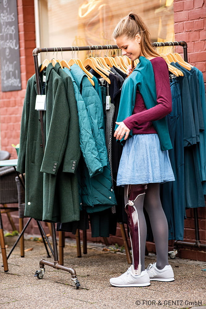 Eine Frau mit Ganzbeinorthese schaut sich gerade nach neuer Kleidung um.