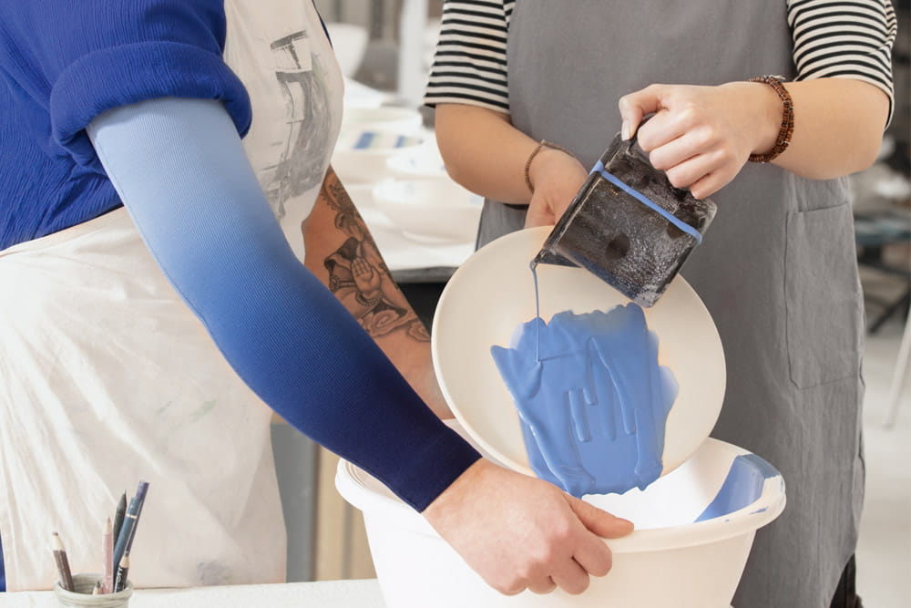 Frauen mit Kompressionsstrümpfen färben Keramik.