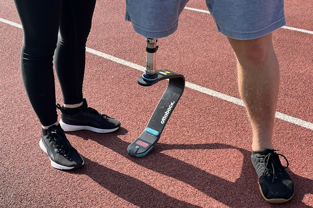 Ein Sportler mit Beinprothese und passender Sportfeder steht auf der Laufbahn.