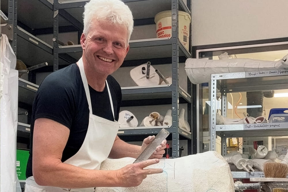 Ein Mitarbeiter vom Orthopädiehaus Scharpenberg steht im Gipsraum mit einer Pfeile.