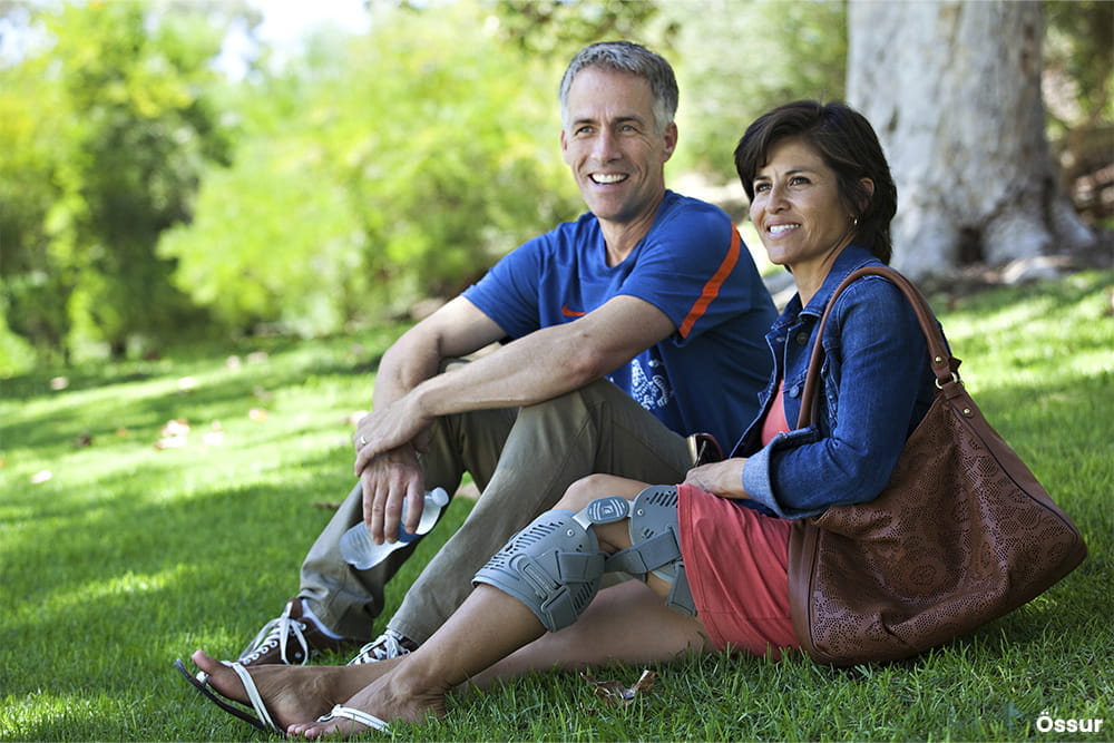 Ein Paar sitzt auf eienr Wiese und die Frau trägt eine Beinorthese.