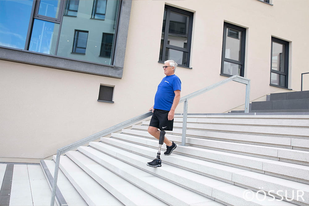 Ein Mann mit blauem T-Shirt und Beinprothese steigt Treppen runter.
