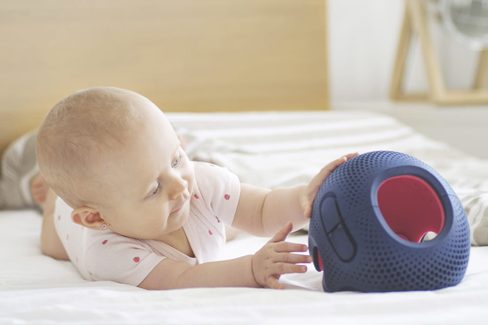 Ein Baby liegt auf einer Matte und es erkundet gerade seinen Orthesenhelm von Talee.